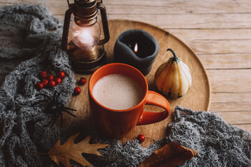 A cup of cappuccino, candles, pumpkin and red berries on wooden tray. Autumn still life. Halloween concept. Top view - obrazy, fototapety, plakaty
