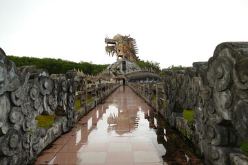 Escultura de dragón en parque acuático abandonado con reflejo de lluvia en el suelo