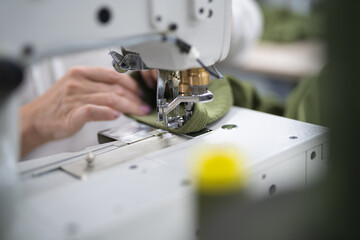 workers in an industrial garment factory sew clothes on sewing machine