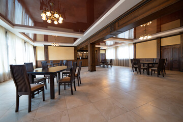 spacious interior of modern empty large restaurant with tables and chairs.