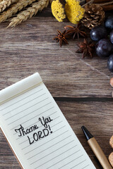 Thank You LORD, handwriting in notebook with wheat and autumn fruit on wooden table. Christian thanksgiving, gratitude, and blessing to God Jesus Christ. Biblical concept.