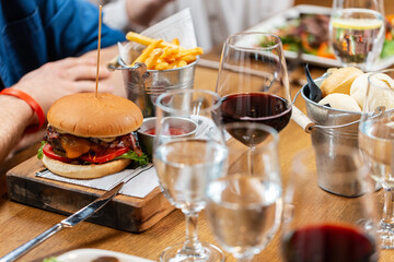 fast food, unhealthy eating and people concept - close up of man eating burger and french fries at restaurant