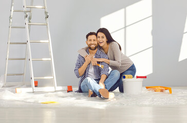 Happy family decorating their house. Cheerful young married couple doing renovations at home....