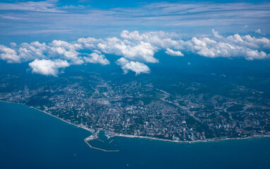 View of the city on the seashore from the window of a flying plane.