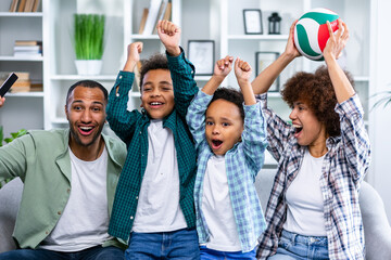 Enthusiastic family of four cheers at home watching sports on TV
