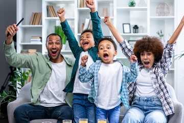Excited family football fans watching sport tv game celebrating goal together, happy parents mom...