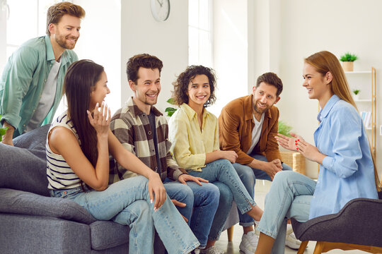 Group Of Young People Hanging Out At Home. Friends Gather At Someone's Place And Have Fun Together. Happy Men And Women Sitting On Couch, Talking About College Life, Sharing Stories And Telling Jokes