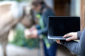 Foto op Plexiglas Horse owner as digital online clients: A laptop in front of blurred horse and owner paddock scene, consulting online advice and online shopping as horse owner © Annabell Gsödl