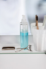 hygiene, beauty and daily routine concept - close up of lotion, toothbrush and toothpaste on mirror shelf in bathroom