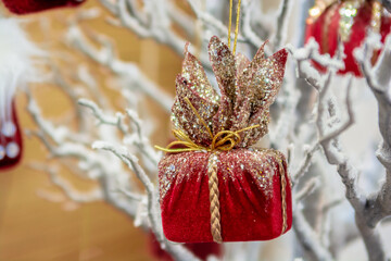 New Year's toy of red color on the branches of a white decorative tree.