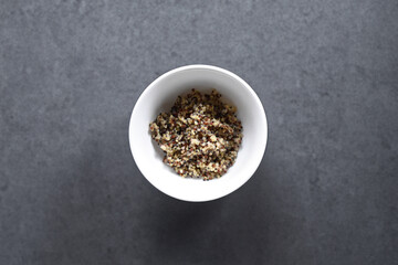 White porcelain bowl with freshly cooked quinoa. On a wooden table. To prepare the salad. Top view