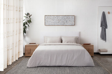 comfortable bed with pillows in contemporary room. interior design wall mock up. white bedroom with rug and gallery on wall above bed. master bedroom with wood furniture. real photo. front view.