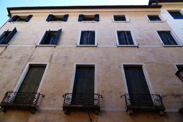 Obraz premium Window house facade with exterior wooden shutters in the historic center of Treviso in the Veneto region, Italy.