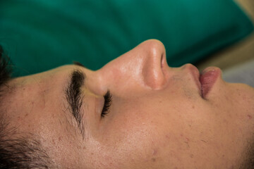 Naklejka premium A close up of a handsome young man laying down with his eyes closed