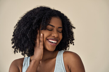 Fototapeta na wymiar Happy young adult African American woman beauty female model, pretty 20s Black lady with curly hair beautiful face advertising skin care products isolated at beige background. Aesthetic authentic shot