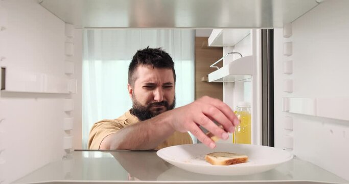 A man, after the party, makes an unexpected discovery of stale bread in the refrigerator. His reaction reflects the aftermath of the gathering, where some food items may have been overlooked.