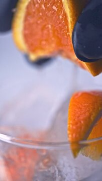 氷の入ったグラスにオレンジを絞る