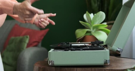 The skilled hands of a Caucasian woman deftly operate a vinyl record player and then join in an elegant dance in the living room. The harmonious movements and her joyful expression.