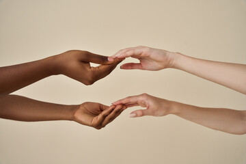 Two different African and European women touching holding hands together isolated on beige...