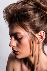 Beauty portrait of model with natural make-up and backcombed hair styling on the white background. Fashion shiny highlighter on skin and gloss lips