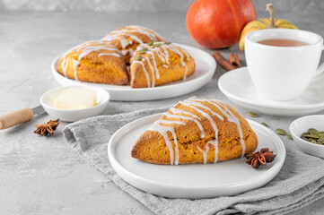 Traditional pumpkin scones with cinnamon, anise and sugar glaze on top. Autumn dessert.