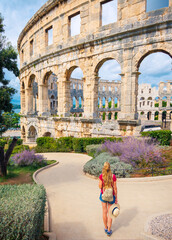Rear view of woman tourist enjoying Pula city with ancient roman amphitheatre- Travel in Europe-...