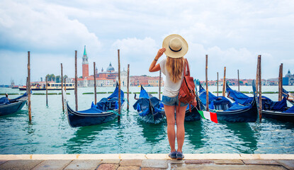 Obraz na płótnie Canvas Rear view of woman standing on embarkment in Venice, Traditional gondola on grand canal, Italy- travel,tour tourism,vacation in Europe