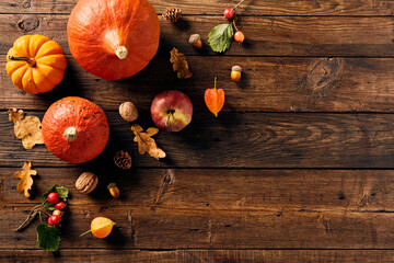 Happy Thanksgiving day concept. Flat lay composition with pumpkins, fall leaves, apple, red berries, walnuts, acorns on wooden desk table.