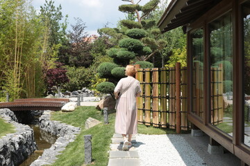 Mature woman walking in the japanese green park in summer.