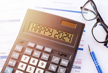 HAPPY 2024 text message on calculator display on workplace background. Concept of happy new year in...
