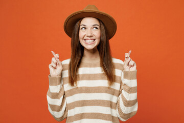Young worried woman she wear striped sweater hat casual clothes keeping fingers crossed, making...