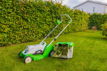 View of trimmed green lawn with electric lawn mower in private house in garden. Sweden.