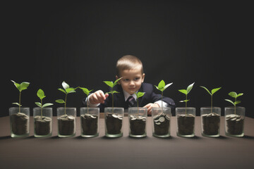A child in a suit and tie observes jars filled with coins with plants growing inside. Financial growth thanks to investment diversification concept.