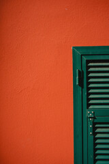 Green wooden shutters on the facade of a red building in Italy, Europe