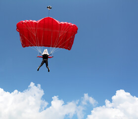 parachutist with red parachute on blue sky extreme sport