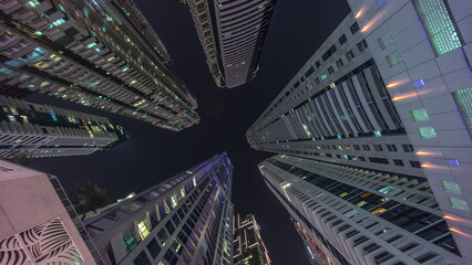 Look up to the night sky with tallest skyscrapers with illuminated windows