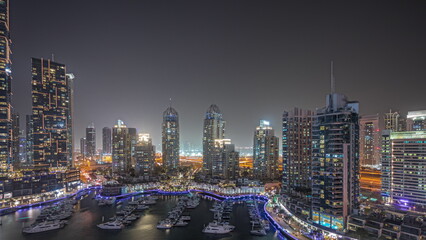 Fototapeta na wymiar Panorama showing Dubai marina tallest skyscrapers and yachts in harbor aerial night.