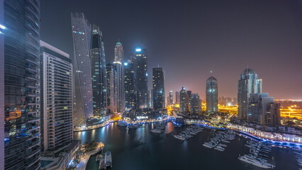 Dubai marina tallest skyscrapers and yachts in harbor aerial all night.