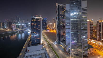 Panorama showing cityscape of skyscrapers in Dubai Business Bay with water canal aerial night