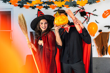 Couple having fun holding pumpkins and wearing dressed carnival halloween costumes and makeup...