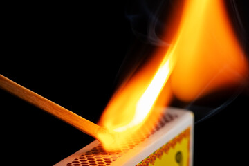 A matchstick lights after it is struck agains the flint surface of a match box. Everything is real,...