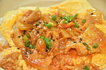 fried pork with kimchi and creamy egg omelets topping on rice in bowl
