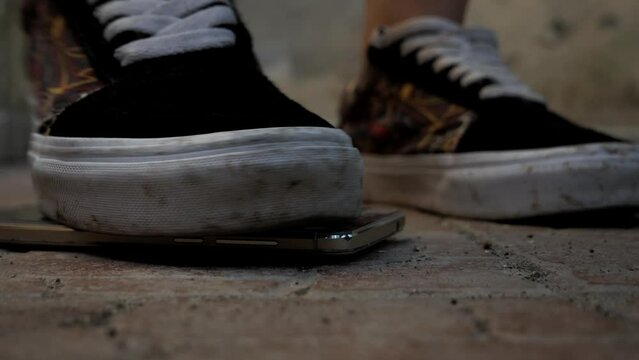 angry young woman steps on a smartphone under her shoe
