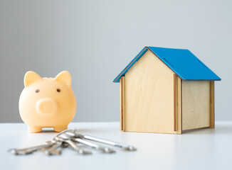 Piggy bank with keys and house model on the table. Savings for buy own home concept. Mortgage, home...