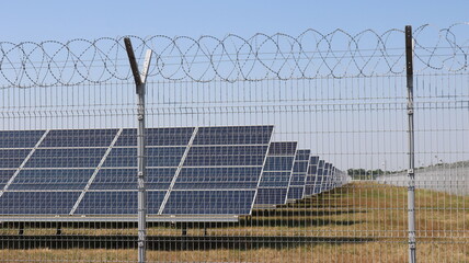 renewable energy obtained from solar panels located in an industrial area surrounded by a wire fence, a station of electrical panels that generate alternative electricity on an industrial scale