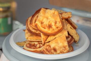 Freshly baked homemade Belgian waffles in a white plastic plate for street vendors. Close-up