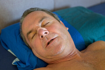 Close up of a sleeping man with a nose tape and open mouth