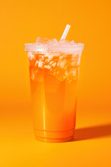 Orange color drink in a plastic cup isolated on a orange color background. Take away drinks concept