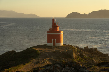Punta Robaleira red lighthouse in Home cape at sunset in Rias Baixas zone in Galicia coast with...