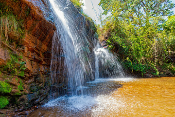 Waterfall among the rocks and forest in the Muaimii environmental reserve in the state of Minas Gerais on a sunny day